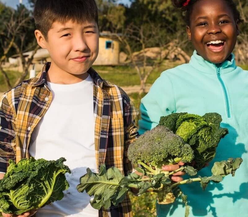 two kids with vegetables from garden